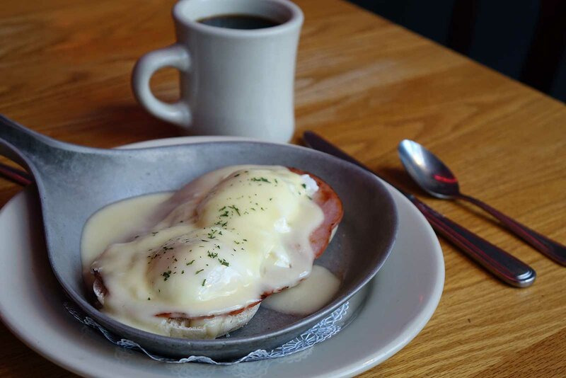 Eggs benedict with ham on top of English muffin covered in hollandaise sauce