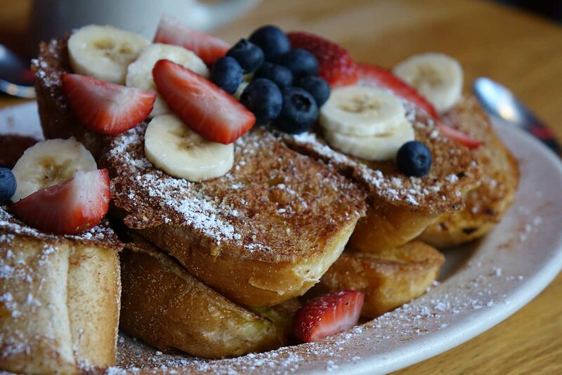 French toast covered with bananas, berries and strawberries